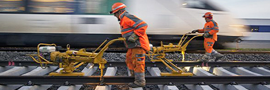 Zwei Bahnarbeiter mit Maschinen auf Gleisen